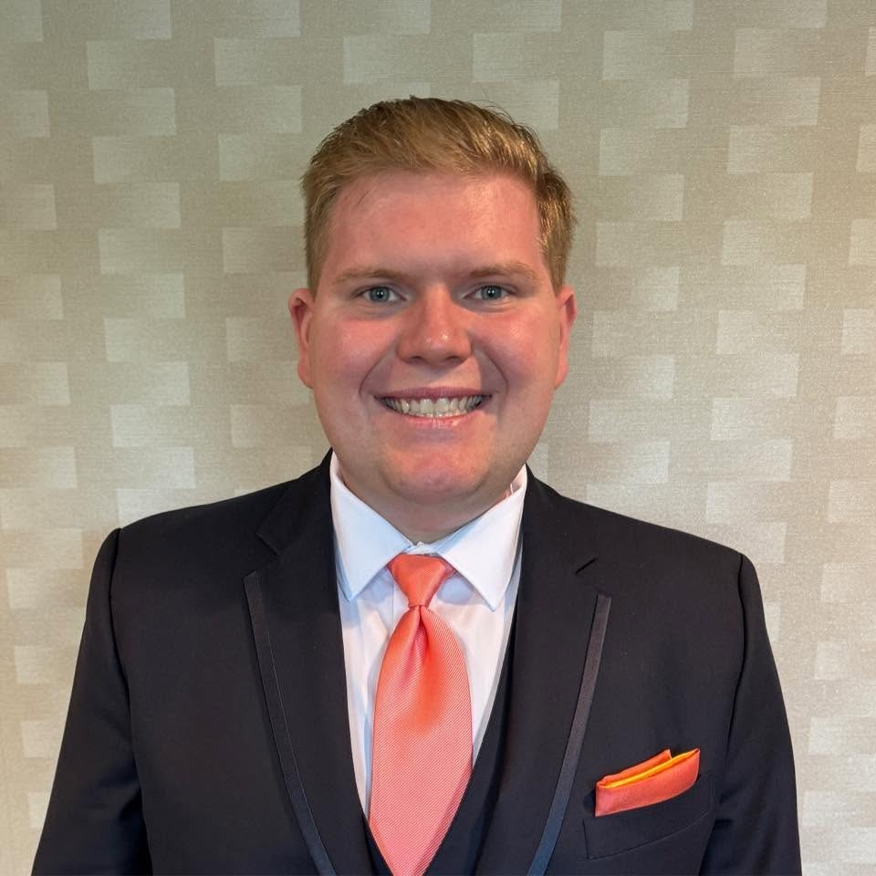 Josh in a suit with an orange tie